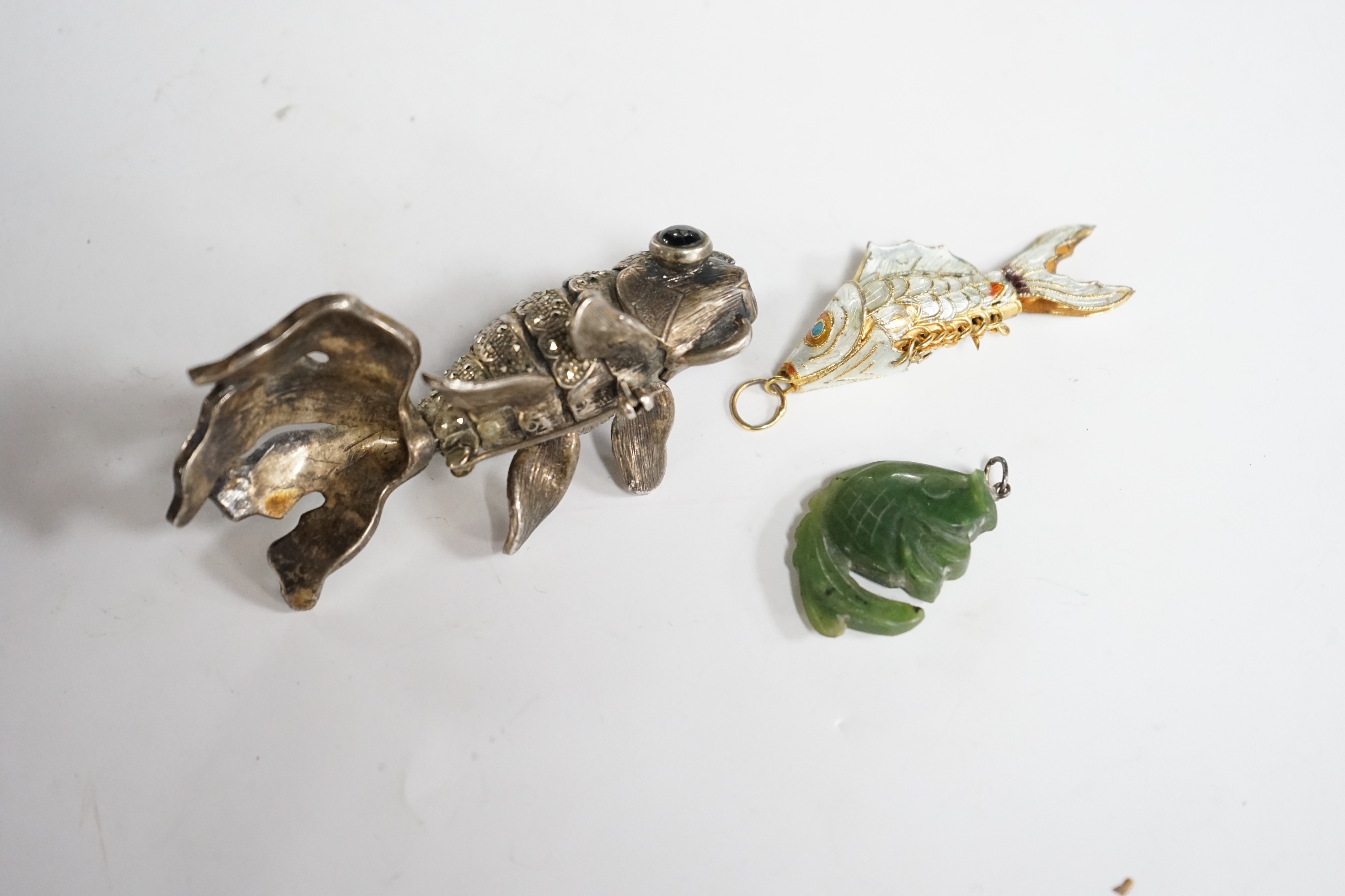 A Chinese? white metal, marcasite and cabochon set articulated model of a telescope goldfish?, 8cm, a gilt white metal and enamel articulated fish charm and a hardstone fish charm.